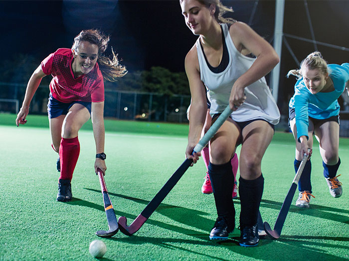 women playing hockey on a multi-sports court